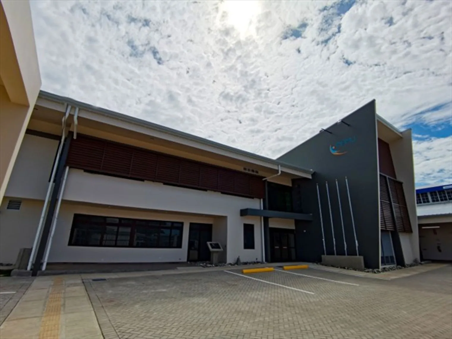 Acceso principal y parqueo de la sede del INAMU en Huetar Caribe, con señalización podotáctil en la acera